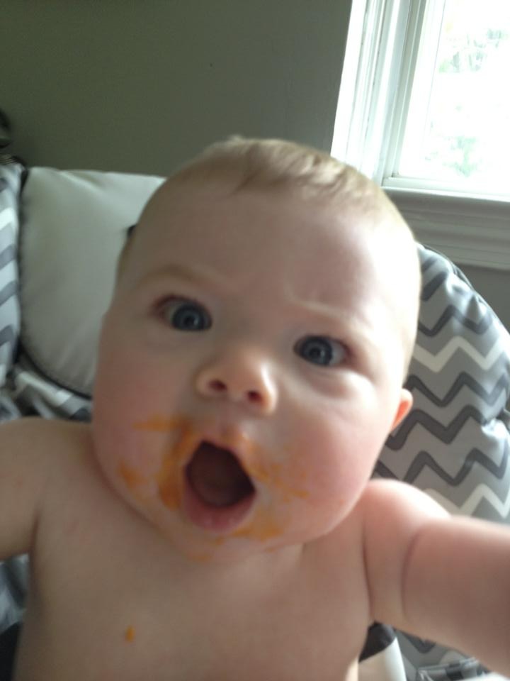 A baby, covered in food with his mouth wide open as if he were screaming