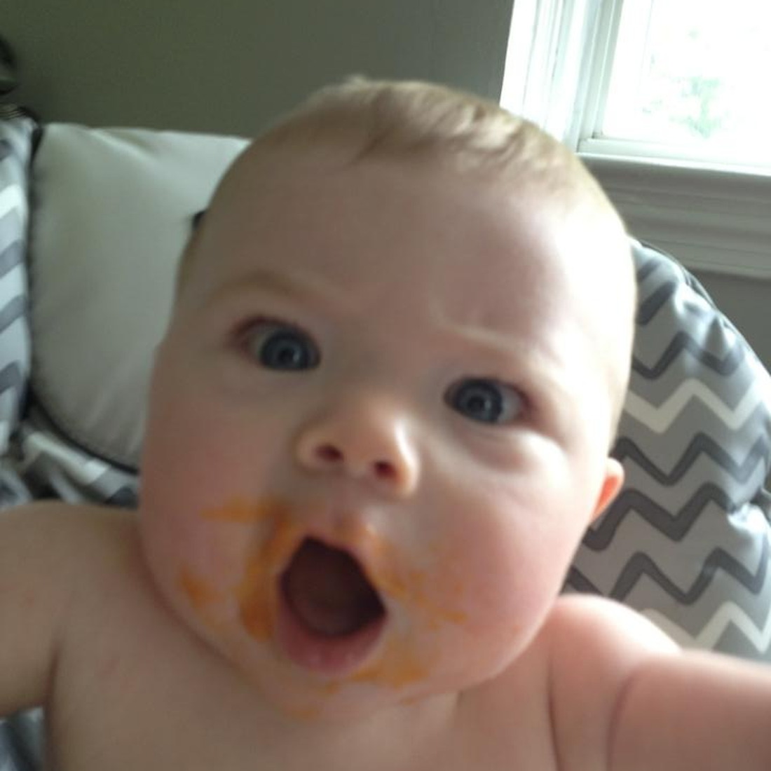 A baby, covered in food with his mouth wide open as if he were screaming