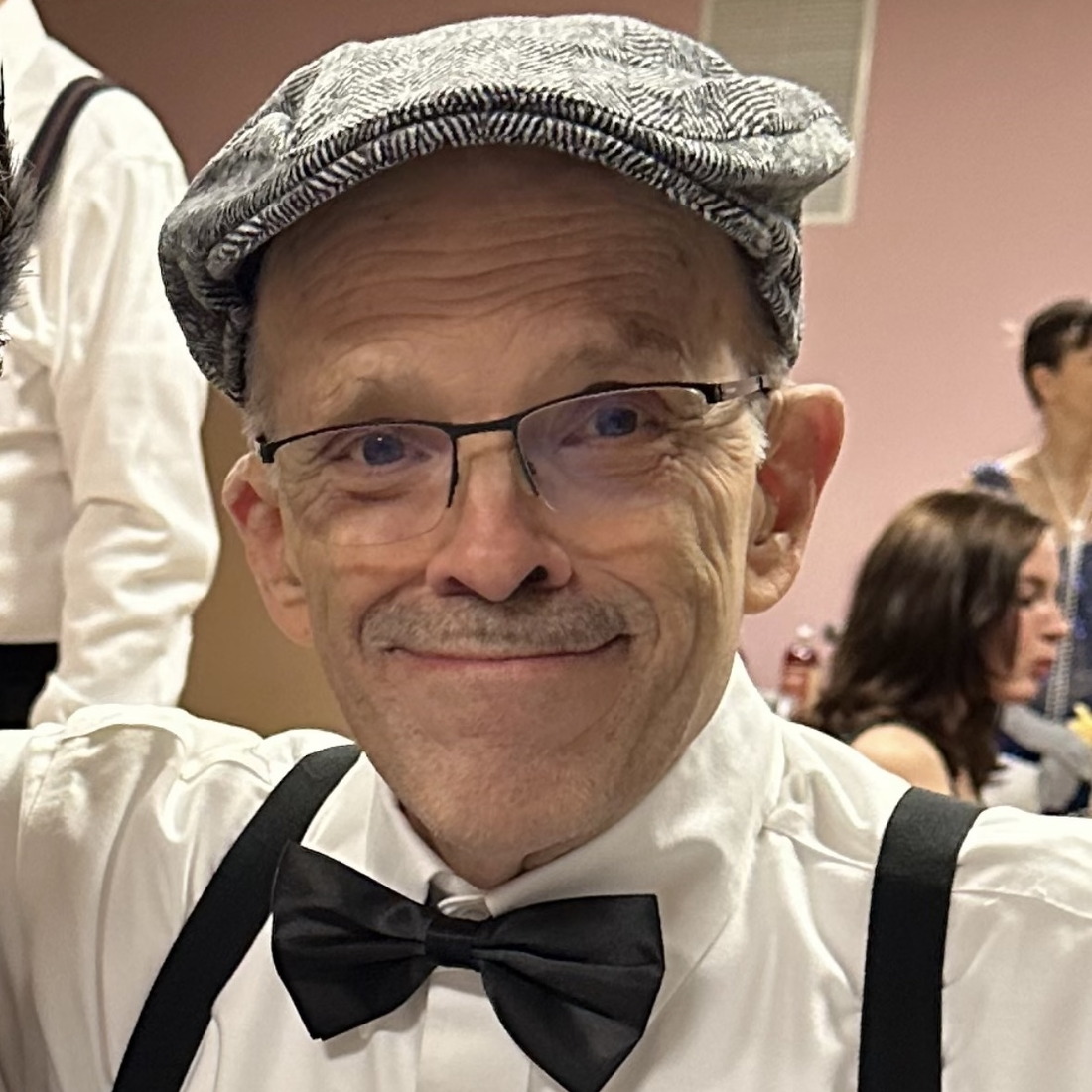 An older gentleman wearing a hat and fancy bowtie
